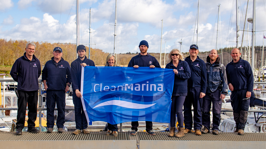 Beaulieu River team members standing in the marina holding a blue Clean Marina flag